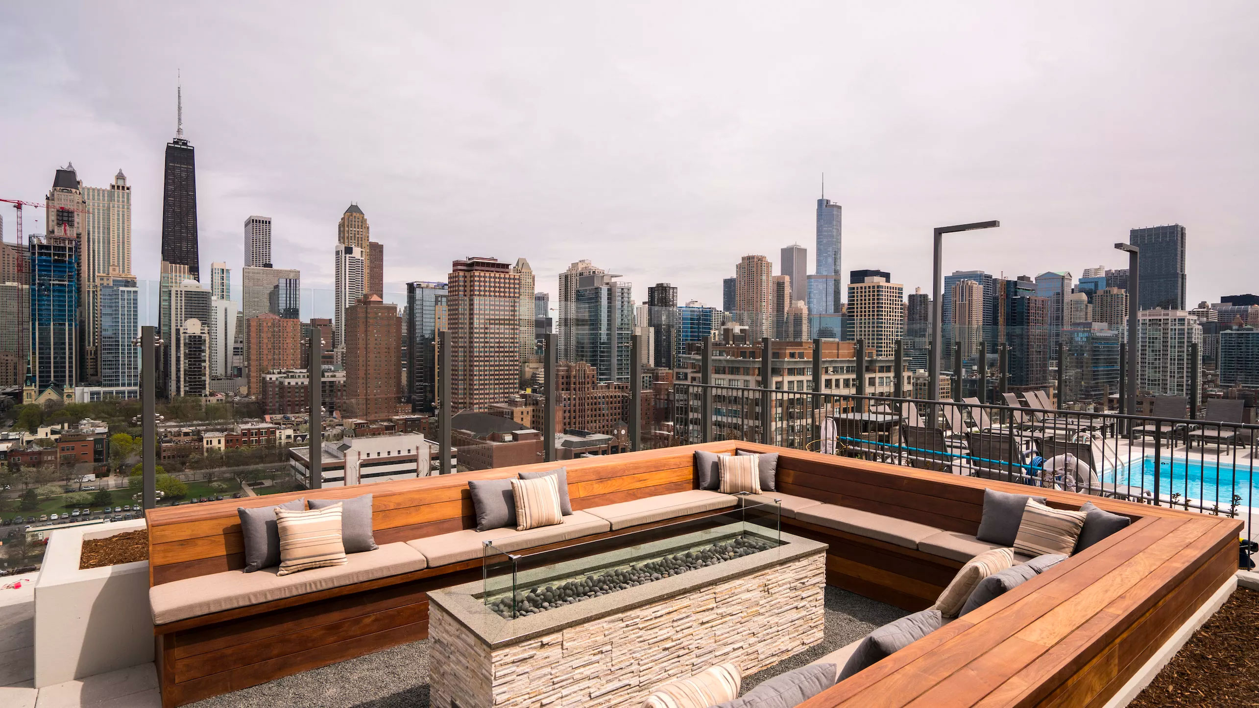 Rooftop fire pit lounge area with pool and city skyline views